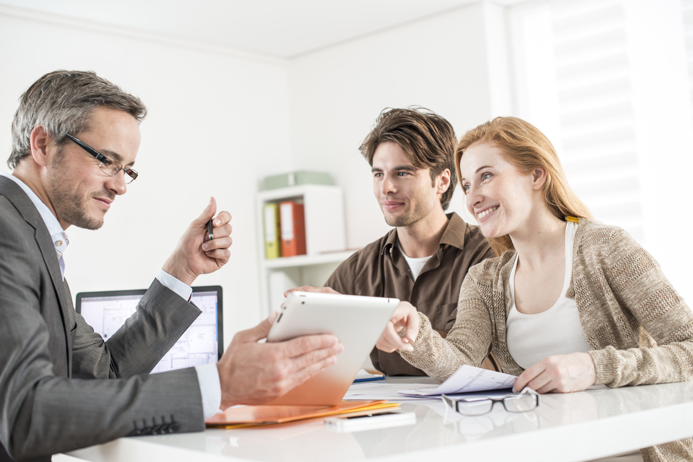 Bank executive explaining personal loan details to a couple during loan approval meeting inside a bank office.