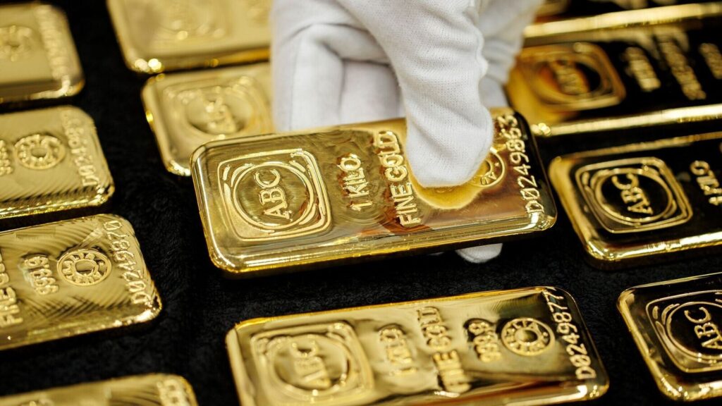 Gold bars stacked with gloved hand symbolizing physical gold investment and gold price forecast